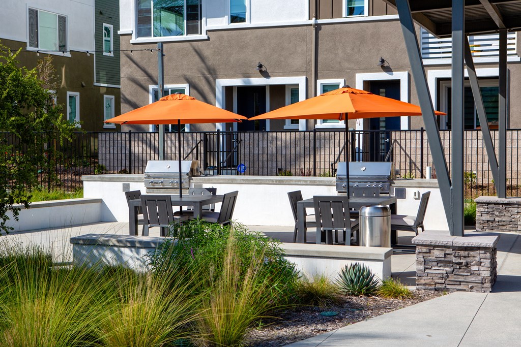 a patio with orange umbrellas and tables and chairs in front of a building