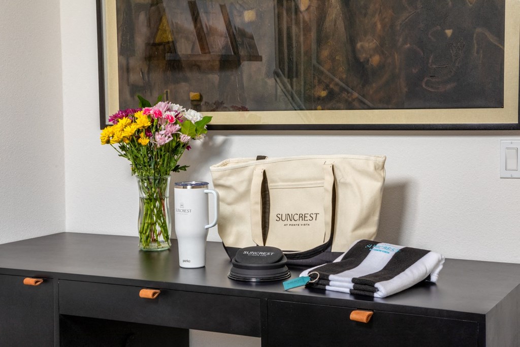 a desk with a bag and a vase with flowers on it