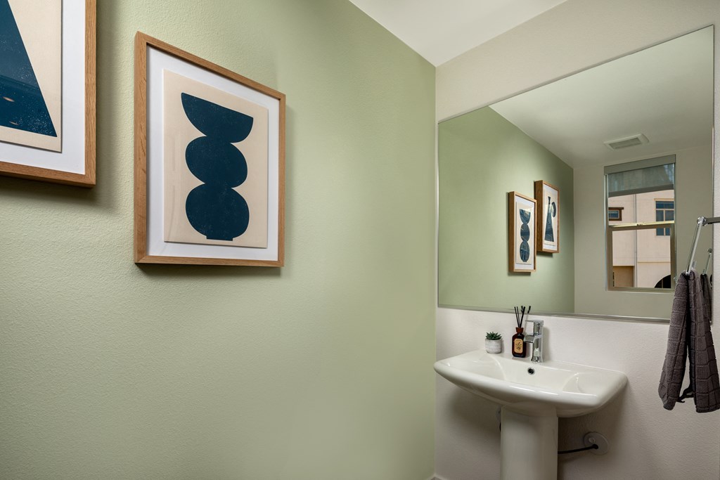 a bathroom with a sink and a mirror and pictures on the wall