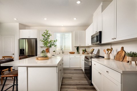 A modern kitchen with white cabinets and a wooden floor.
