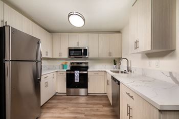 A kitchen with a stainless steel refrigerator and wooden cabinets.