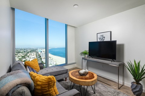 a living room with white walls and a large window with a view of the ocean