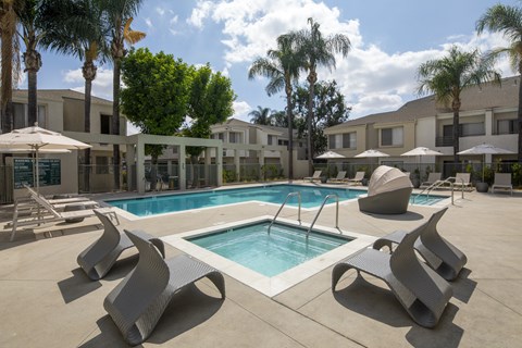 A pool surrounded by palm trees and a building.