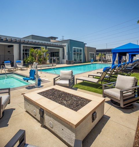 a swimming pool with lounge chairs and a fire pit