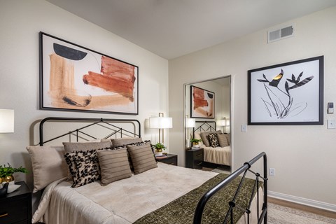 A bedroom with a large bed and two framed artworks on the wall.