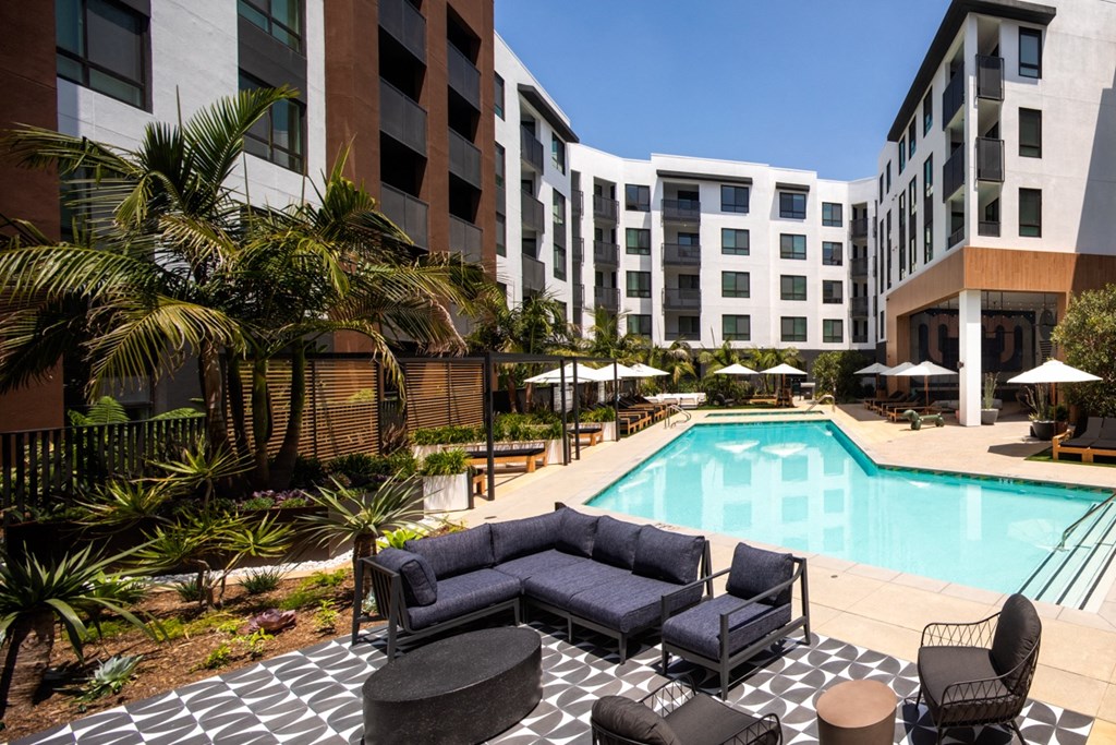 a swimming pool with a couch and chairs in front of a building