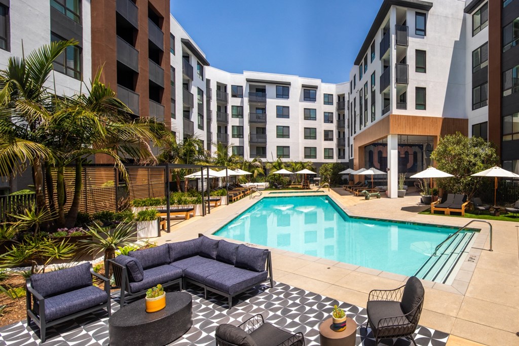 a swimming pool in front of a hotel with couches