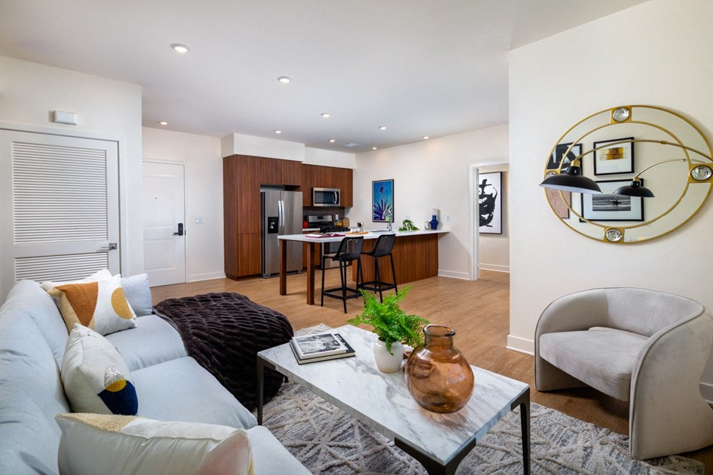 a living room with a couch and a table in front of a kitchen