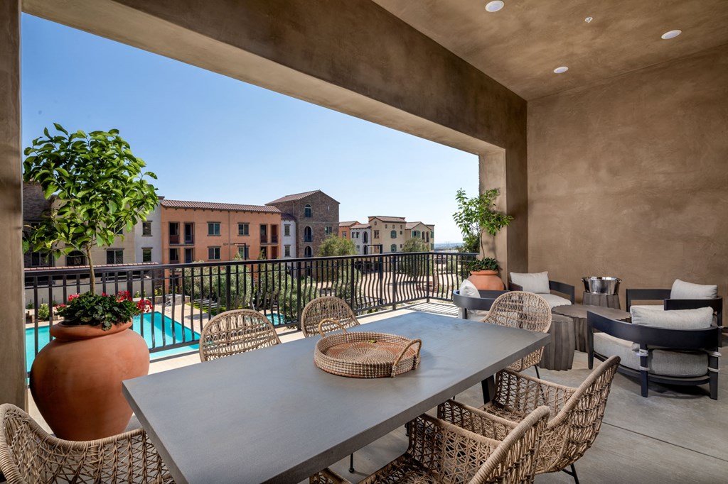 a patio with a table and chairs and a pool in the background