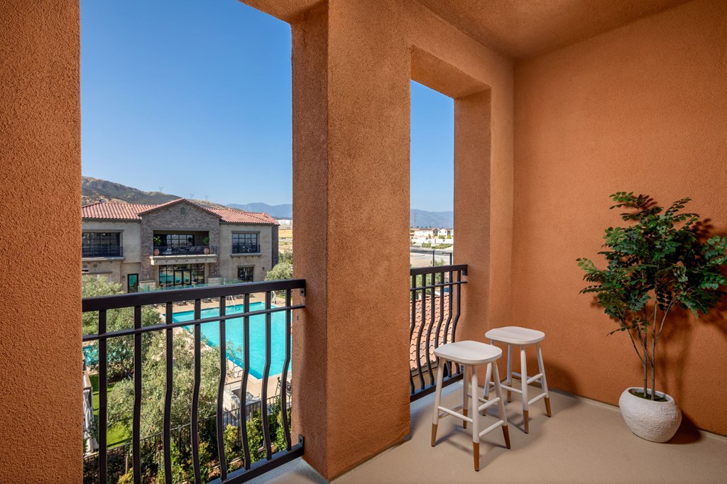 a balcony with two stools and a plant