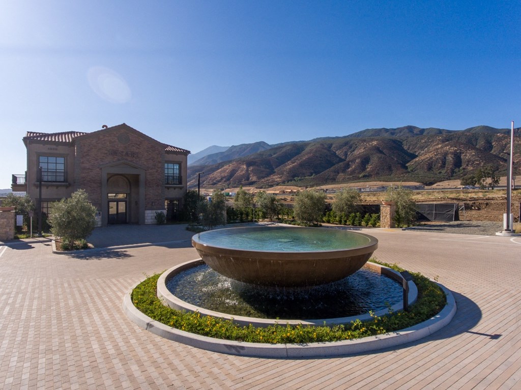 a fountain in front of a building with mountains in the background