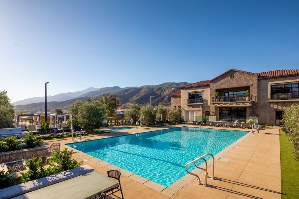a swimming pool in front of a hotel with mountains in the background