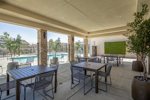 A patio with a table and chairs overlooking a pool.