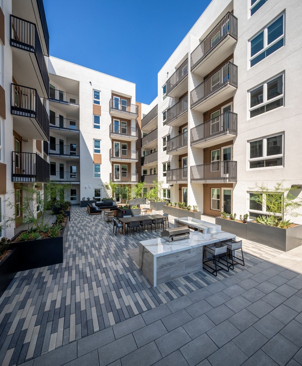an outdoor patio with a firepit and tables surrounded by apartment buildings at VORA LUX, San Diego California