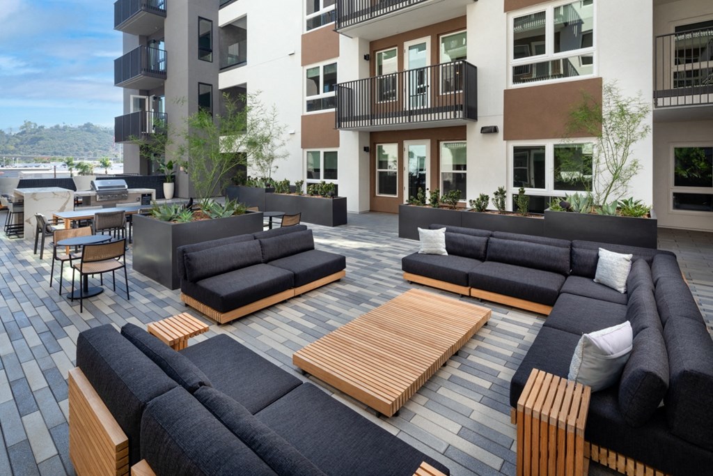 a patio with couches and tables in front of an apartment building at VORA LUX, California, 92120