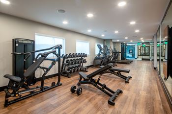 a gym with cardio equipment and weights on a wooden floor and smart fitness Mirror at VORA LUX, Mission Valley, California, 92120