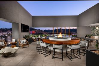 a patio with a fire pit and a view of a city at night