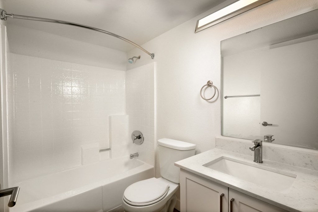A white bathroom with a toilet, sink, and tub.
