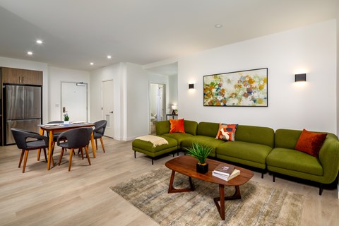 A modern living room with a green couch and a wooden coffee table.