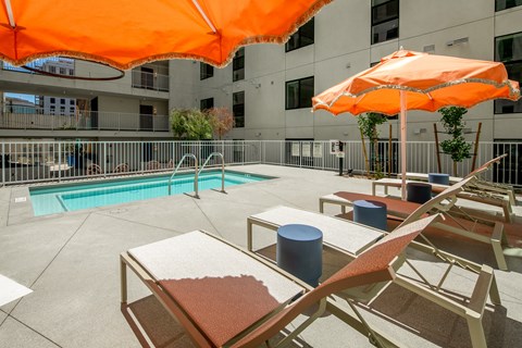 A pool area with sun loungers and an orange umbrella.