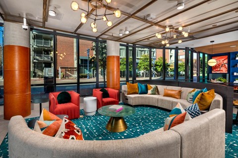 A modern living room with a round coffee table and a variety of colorful pillows.