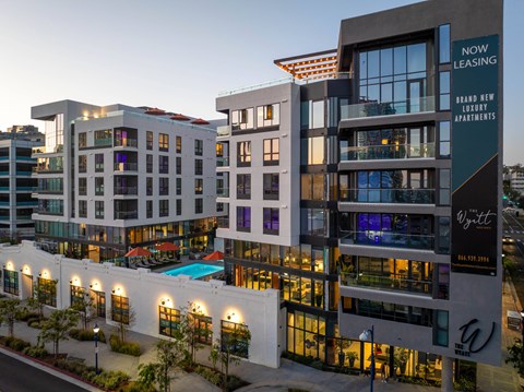 A modern apartment complex with a pool and a sign that says "Now Leasing".