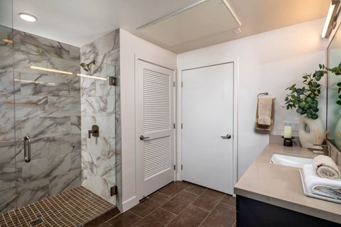 A bathroom with a marble shower and a white door.