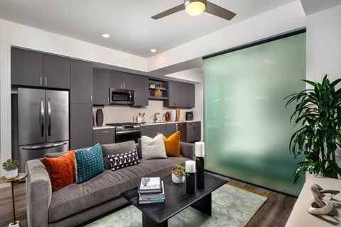 A modern living room with a grey couch and a glass wall.