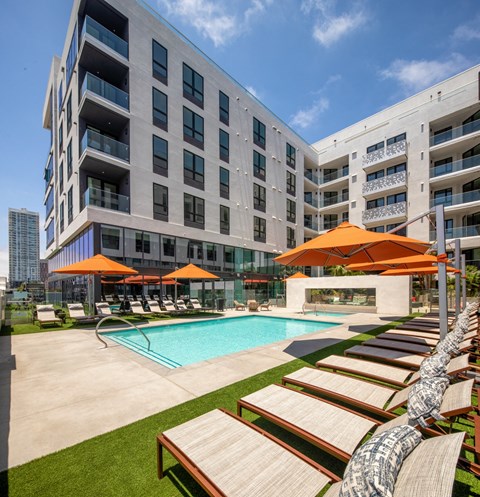 a pool with lounge chairs and umbrellas in front of a building