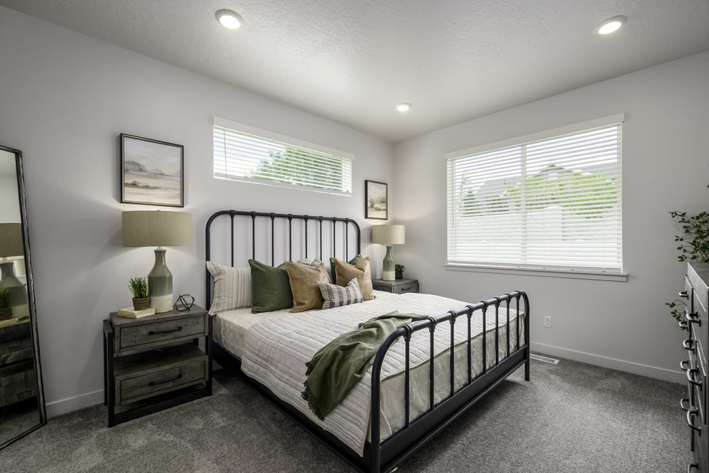 the master bedroom in a new home with a bed and two windows