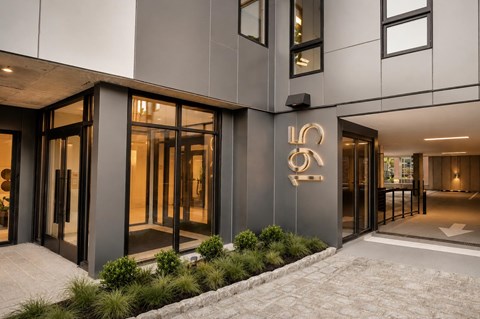 The image shows a modern building entrance with a large glass door and a sign with the letters "LO".