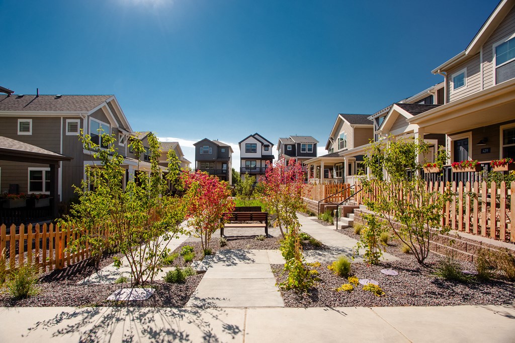 a group of houses with a walkway and benches in a garden