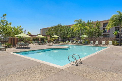 A large swimming pool surrounded by chairs and umbrellas.
