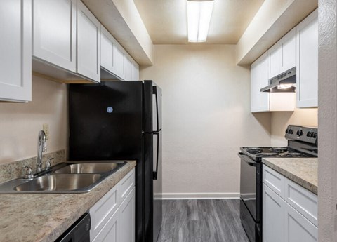 a kitchen with white cabinets and a black refrigerator