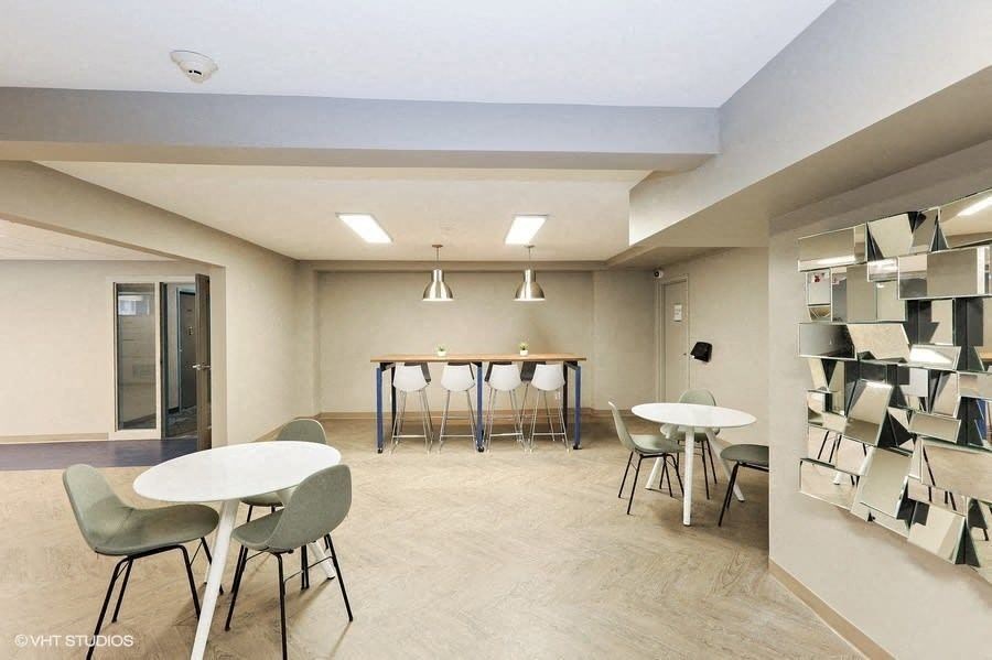 a room with tables and chairs and a bookshelf