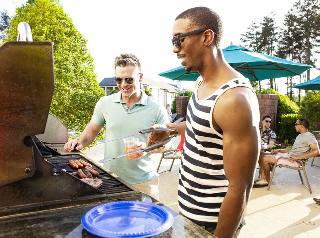 a couple of men standing in front of a grill at The Madison at Adams Farm, Greensboro