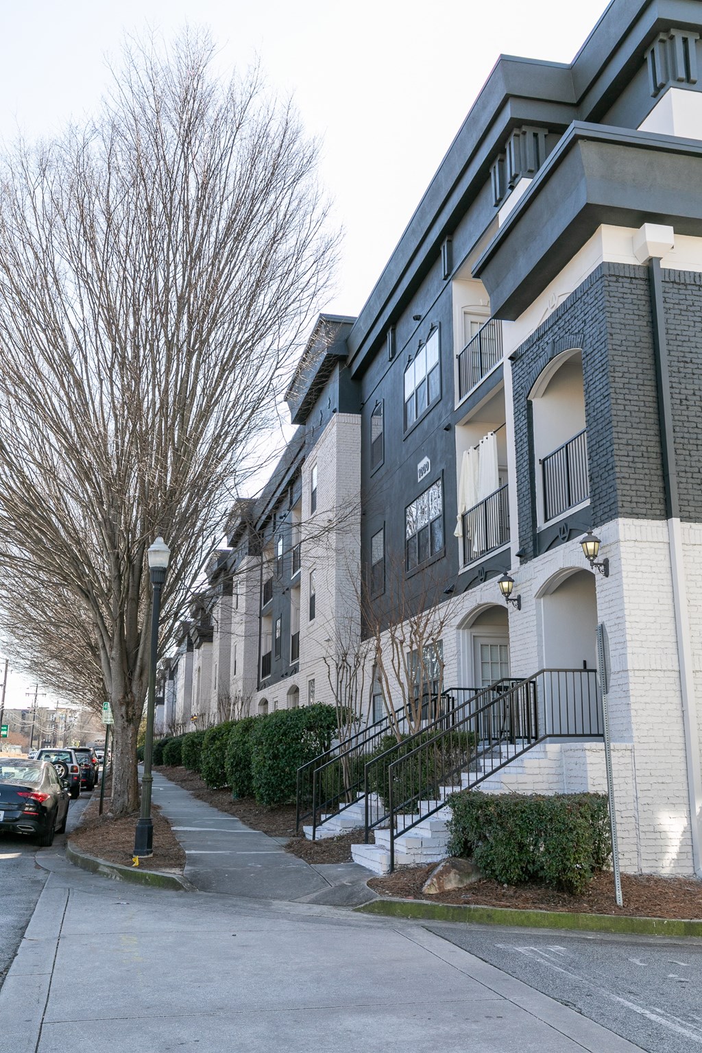 a row of apartment buildings on a street with cars parked on the side of the road