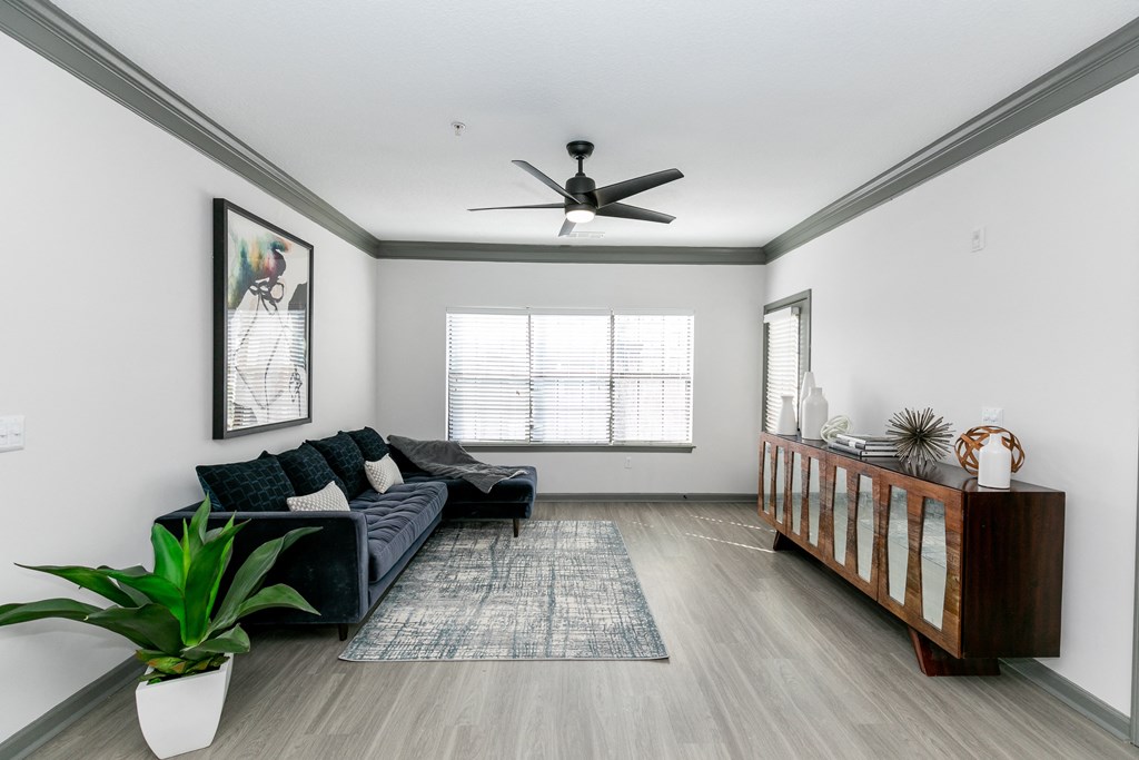 a living room with a couch and a couch in front of a window with a ceiling fan