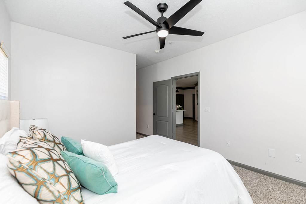 a bedroom with white walls and a ceiling fan
