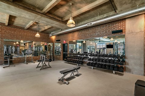 A gym with a variety of equipment including weights and benches.