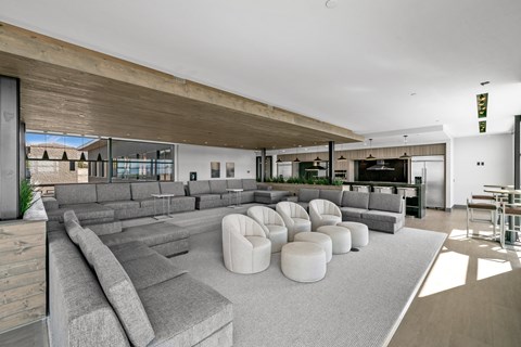 A modern living room with a large grey sofa and a wooden ceiling.