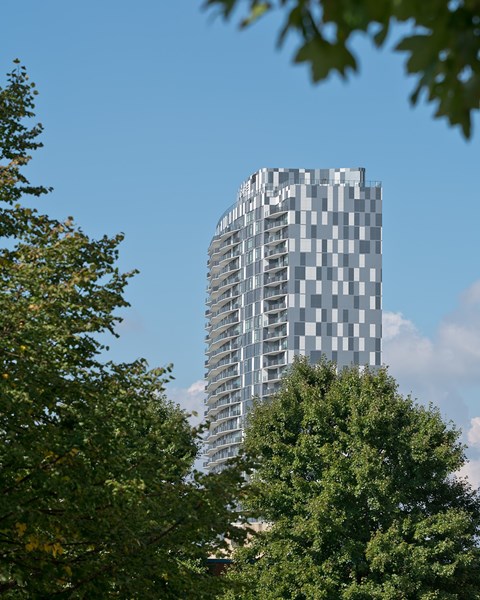 A tall building with a checkered pattern is surrounded by trees.