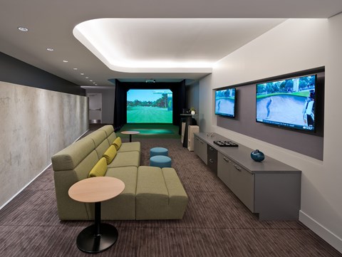 A modern living room with a large couch and two TVs mounted on the wall.