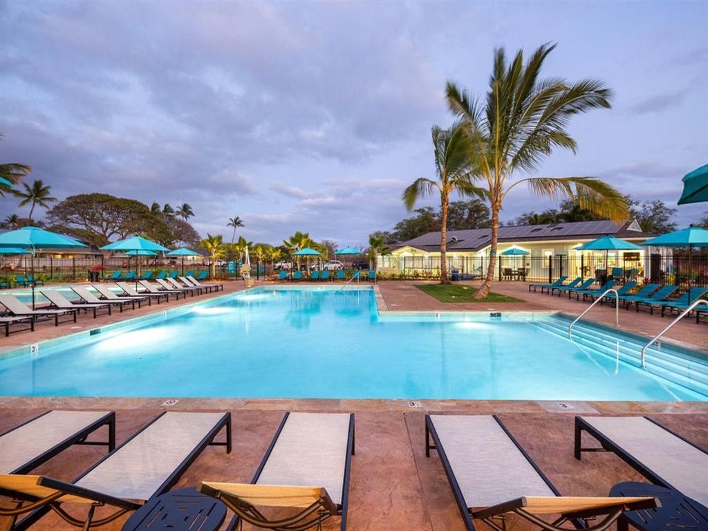 a swimming pool with chairs and umbrellas at a resort