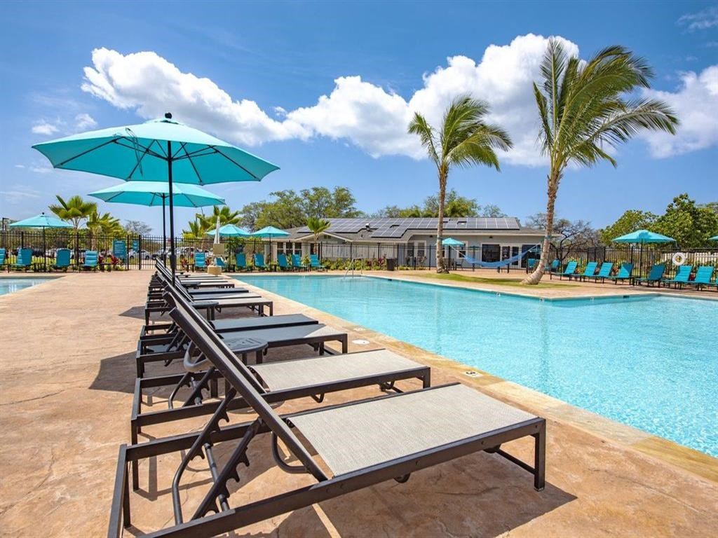 a large swimming pool with picnic tables and umbrellas