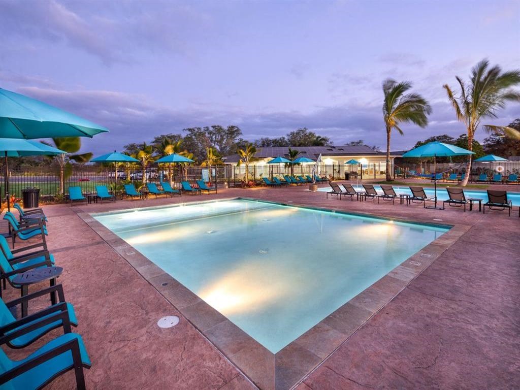 a swimming pool with chairs and umbrellas at night