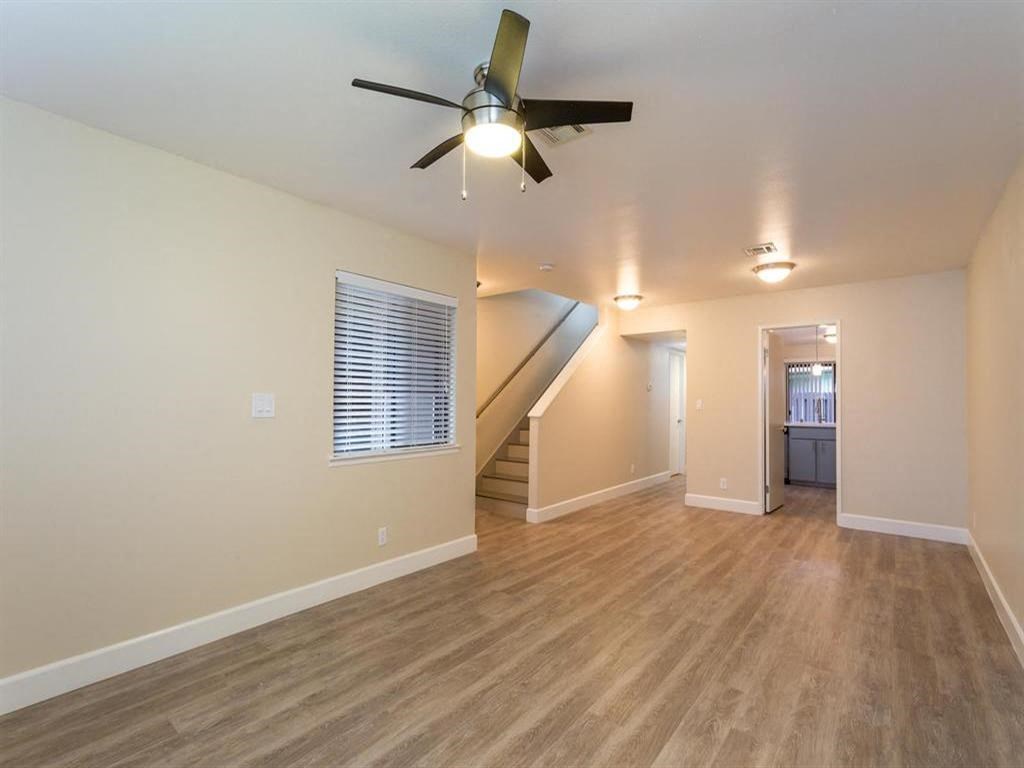 a living room with a ceiling fan and a staircase