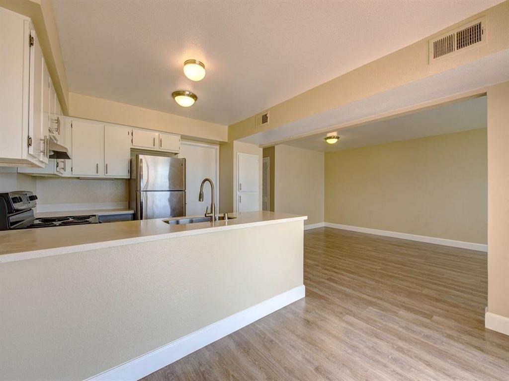 an empty kitchen and living room with a sink and refrigerator