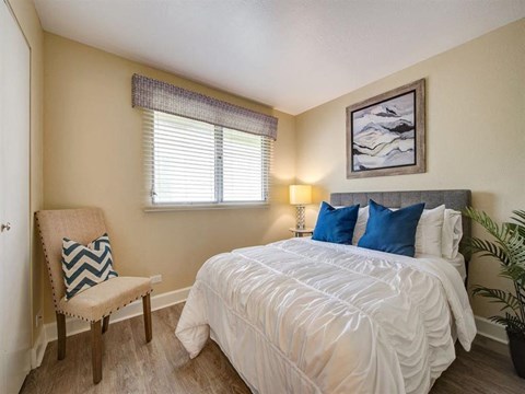 a bedroom with a bed and a chair and a window