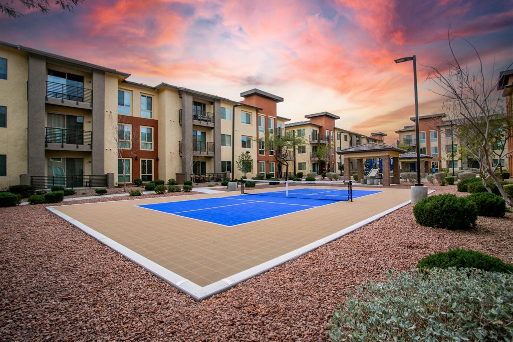 an outdoor pickleball court with apartments in the background